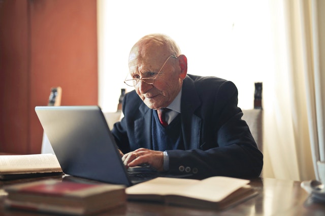 Alt-tag: An elderly man typing on a laptop. 